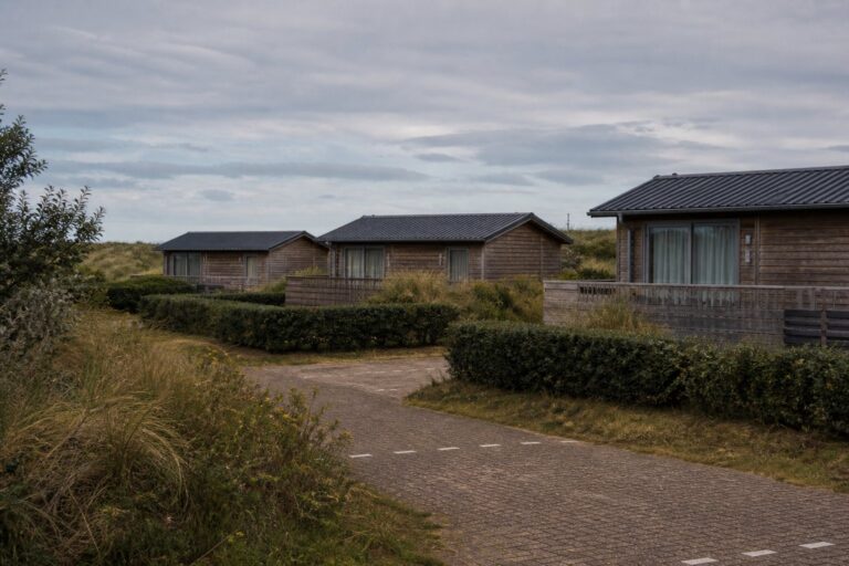 Rij houten vakantiehuisjes op een stil vakantiepark in de duinen